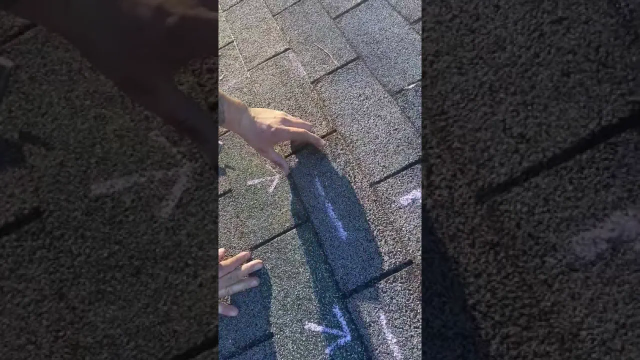 A Robin Hood Roofing inspector pointing to chalk-marked hail damage on a roof shingle during a free inspection