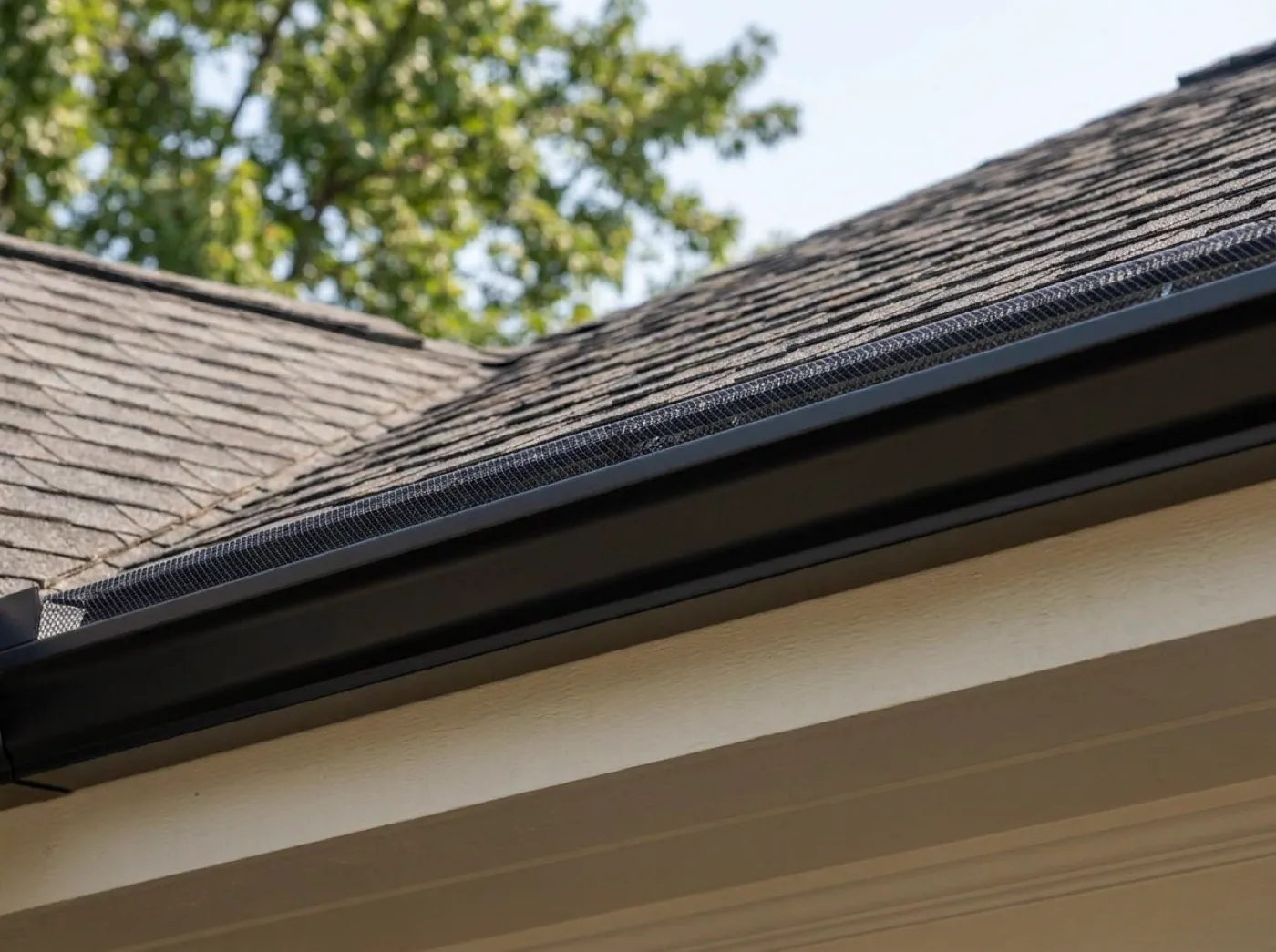 Newly installed seamless aluminum gutters with mesh gutter guards along a roof edge
